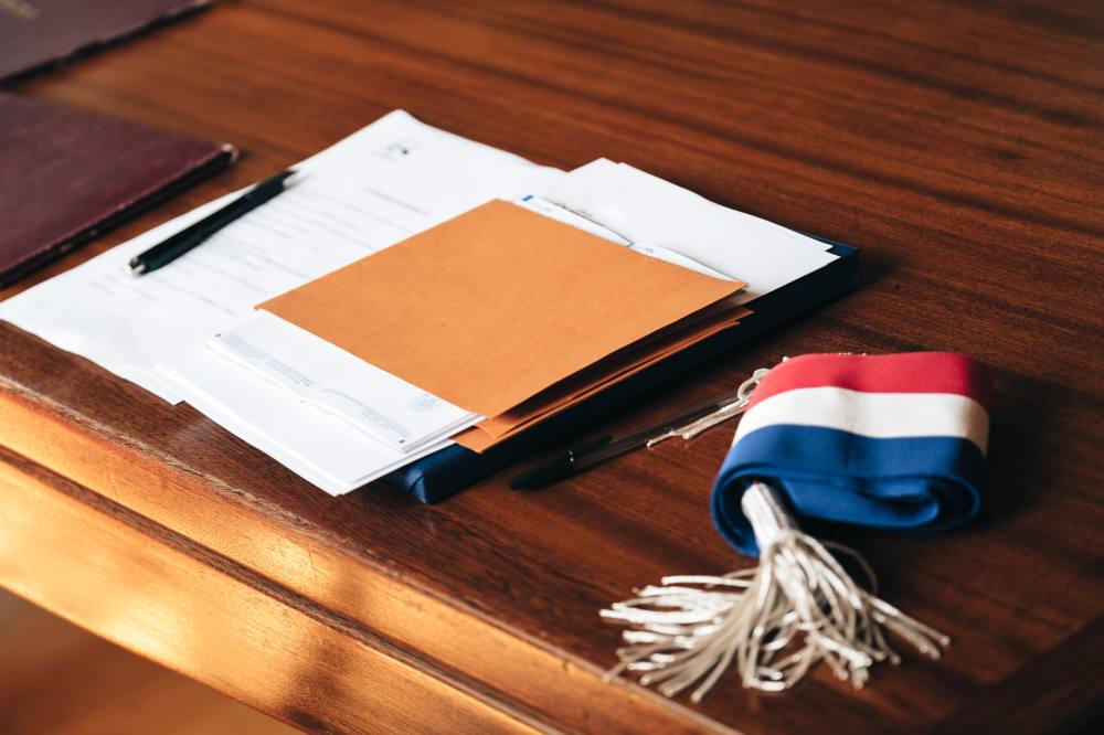 Écharpe tricolore et dossiers posés sur la table du conseil
